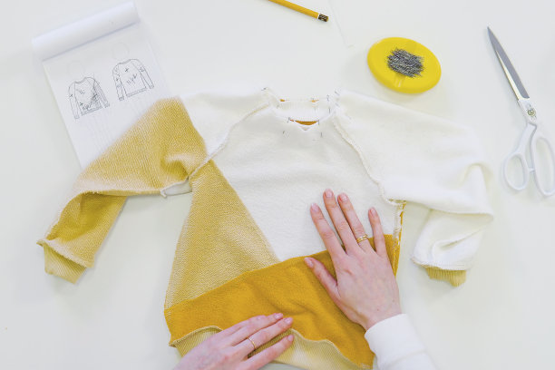 时装设计师或裁剪面料，而工作与绘图草图，材料在工作台。服装经营理念。从上面看图片下载