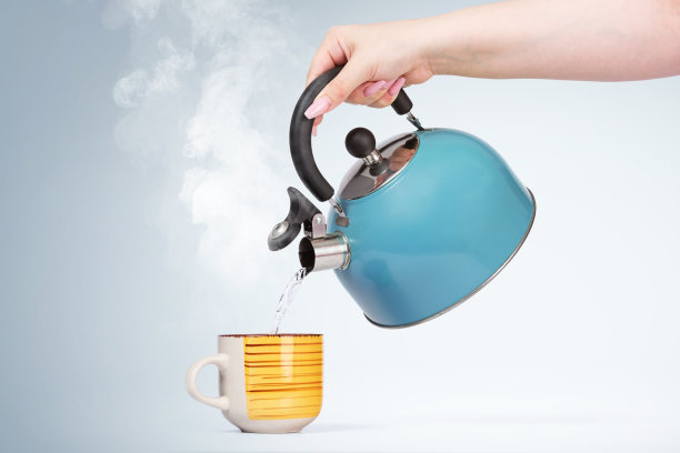 女人的手将热水从一个蓝色的水壶倒进一个有饮料的杯子里，背景是浅色的图片下载