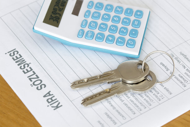 后面的木桌上放着租赁协议书，上面有计算器和钥匙。图片下载