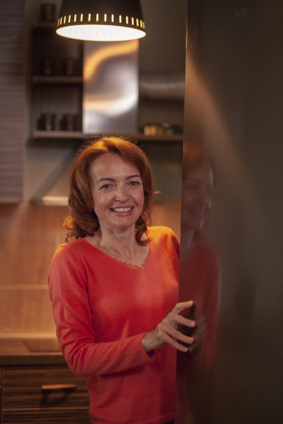 一个快乐的女人，打开冰箱的门。上半身照片图片下载