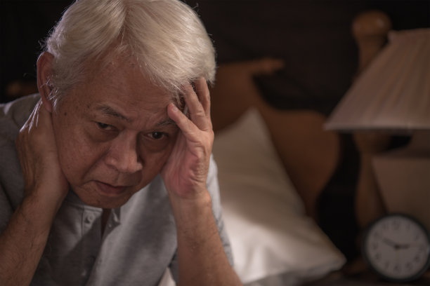 一个沮丧的老年人坐在床上无法入睡图片下载