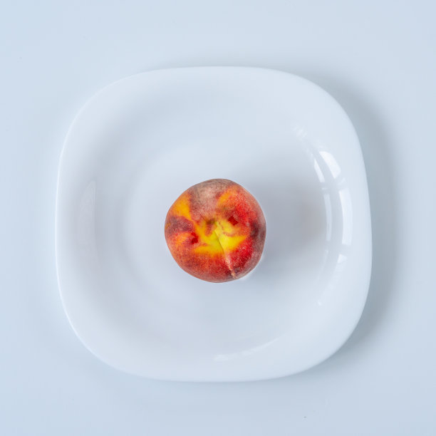 白桌子上白盘子上的桃子。吃饭时间，早餐，午餐时间和晚餐的概念。饮食的概念。图片下载