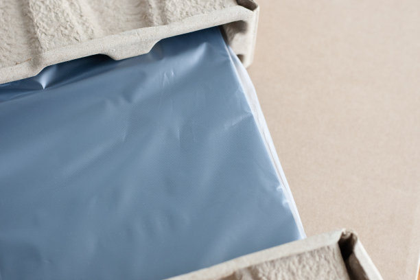 在木桌前打开新的蓝色笔记本电脑。玻璃纸包装。邮政和交付概念。图片下载