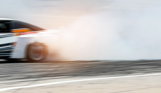 赛车车轮漂移。模糊的图像扩散赛车漂移与大量烟雾从燃烧的轮胎在高速轨道上。运动概念，漂移汽车概念图片下载