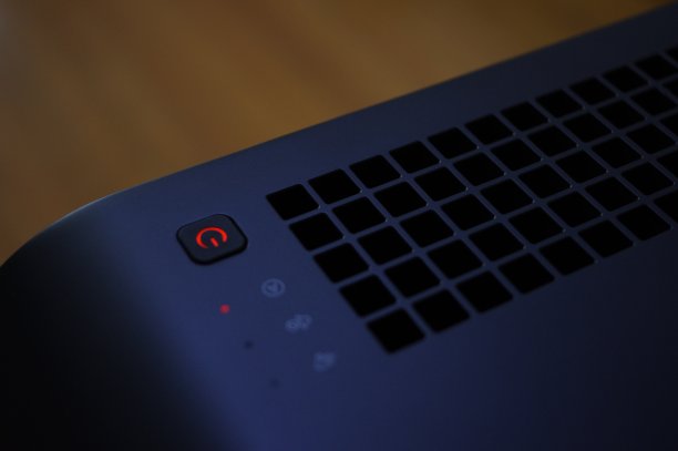 黑色电动空气净化器排气栅出风口和橙色发光电源按钮自动模式图片下载