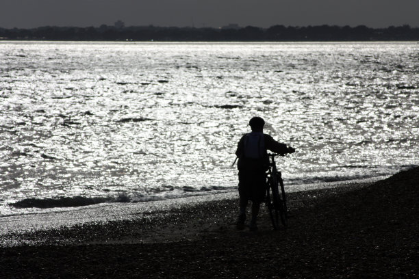 海滩上骑自行车的人的剪影图片下载
