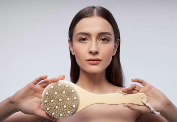 漂亮的女孩与按摩刷站在浅蓝色的背景图片下载