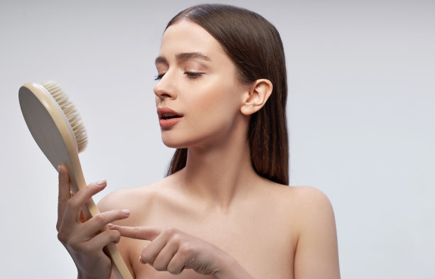 美丽的年轻女子看着按摩刷在她的手中图片下载