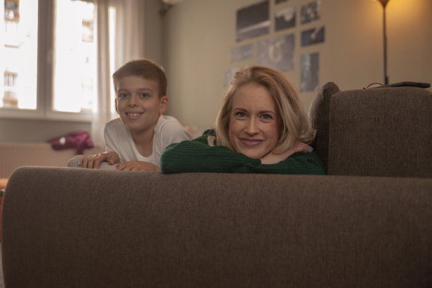 两个人，年轻的女人和男孩，看着相机，就像在他们的客厅里的全家福。图片下载