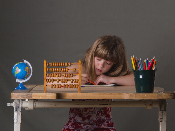 一个勤奋好学的小女孩坐着用彩色铅笔画画图片下载