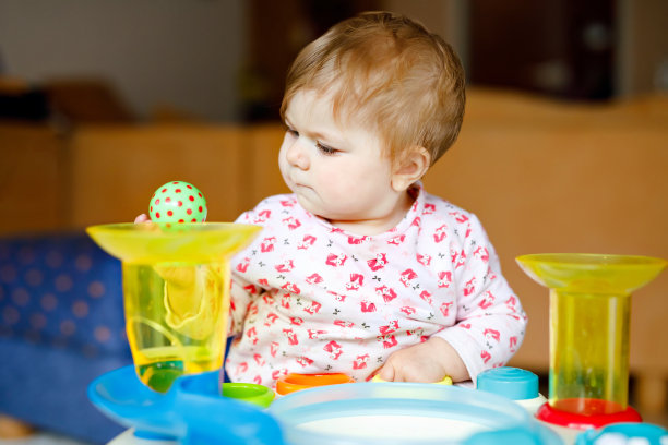 可爱可爱的小女孩在家里或托儿所玩益智玩具。快乐健康的孩子有乐趣和分类彩色不同的塑料球。孩子学习不同的技能图片下载