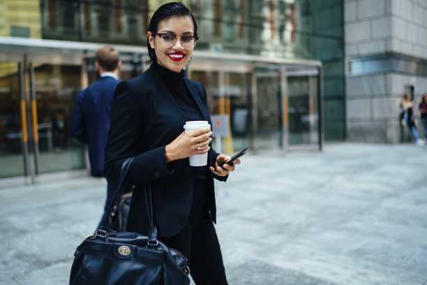 这是一幅半长肖像，照片中是在金融区的城市环境中，愉悦的女经理在镜头前微笑着，成功的女老板穿着优雅的衣服，戴着眼镜图片下载