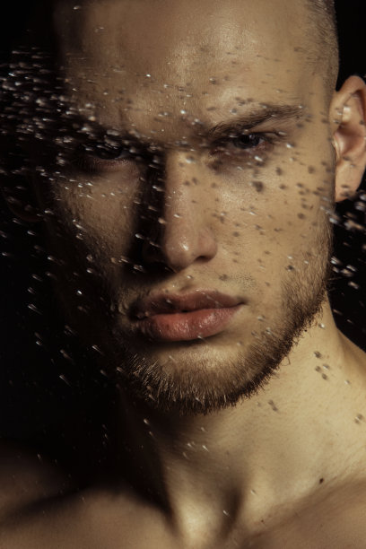 英俊的运动性感的男子肖像在水与化妆品在孤立的黑色背景图片下载