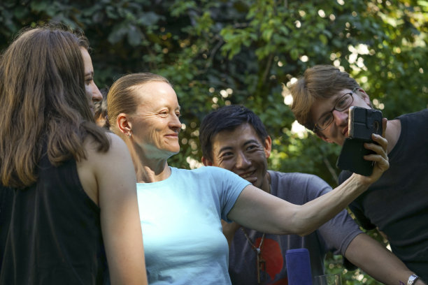 两名男子和两名女子在手机上观看视频，以绿色树叶为背景图片下载