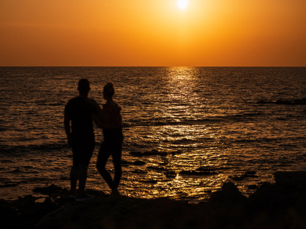 年轻夫妇欣赏日落时宁静的大海图片下载