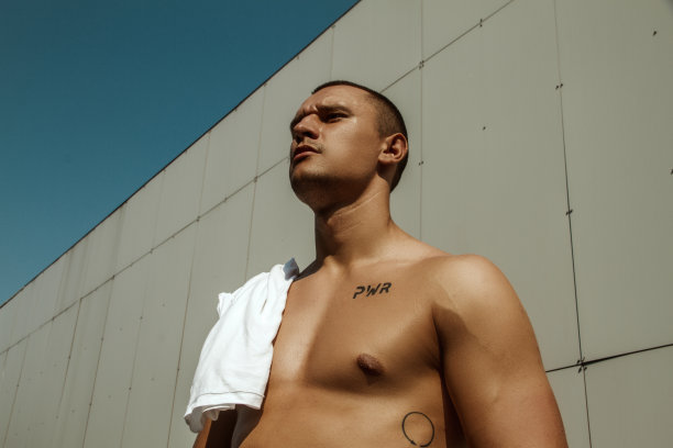 英俊的运动肌肉美丽的条纹男模特在牛仔布和白色衬衫在田径运动的背景图片下载