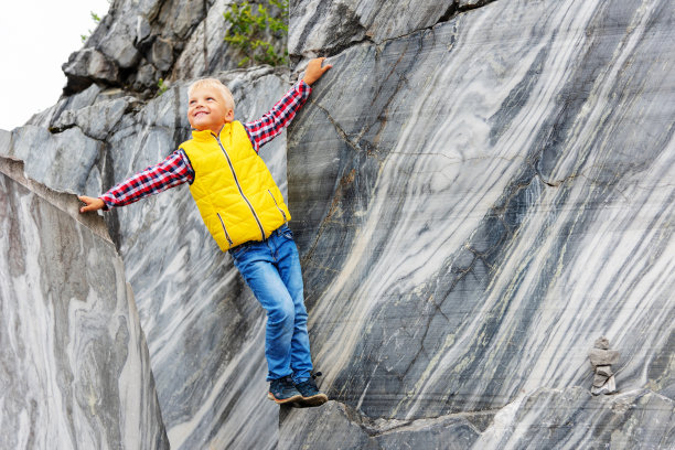 那个男孩正站在一块岩石上。天然建筑材料——大理石图片下载