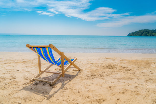 一个沙滩椅在白色的沙滩上，蓝天和夏日的大海背景。夏季，假期，旅游和假日概念。图片下载