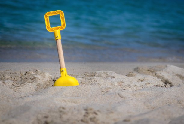 沙堡用铲子挖进沙滩上的沙子。图片下载