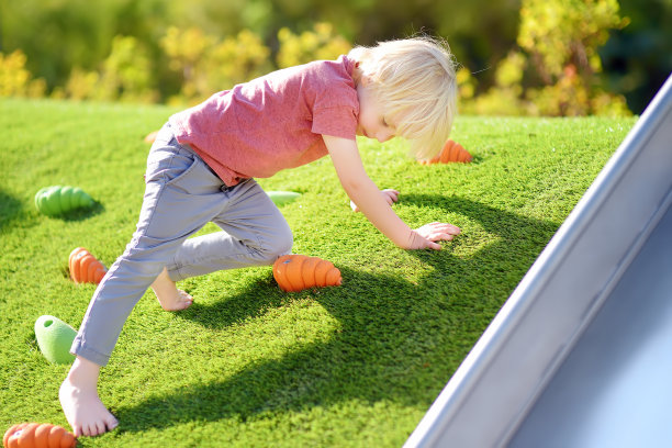 在阳光明媚的夏日，小男孩在公园的户外操场上玩耍。图片下载
