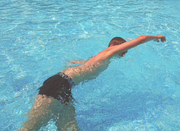 一个少年在游泳池里游泳图片下载