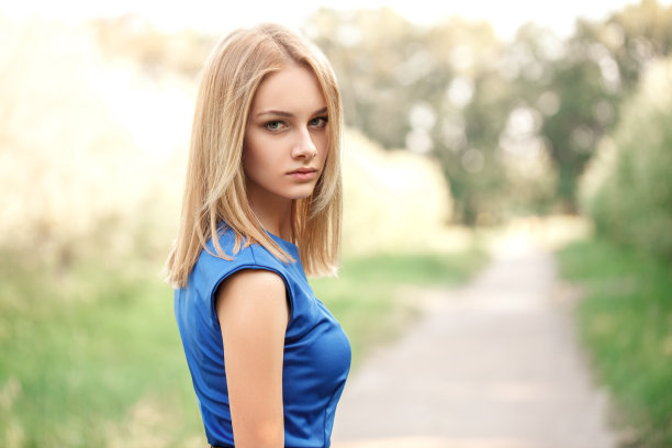 自由。穿着衣服的年轻女子站在公园里，自信地回头看近景模糊的背景图片下载