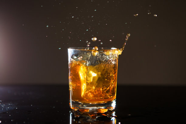 一杯威士忌与溅在黑色背景图片下载