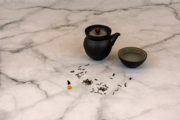 亚洲茶座与铁制茶壶碗和干树叶在大理石桌子上，在极简主义的背景与复制空间图片下载