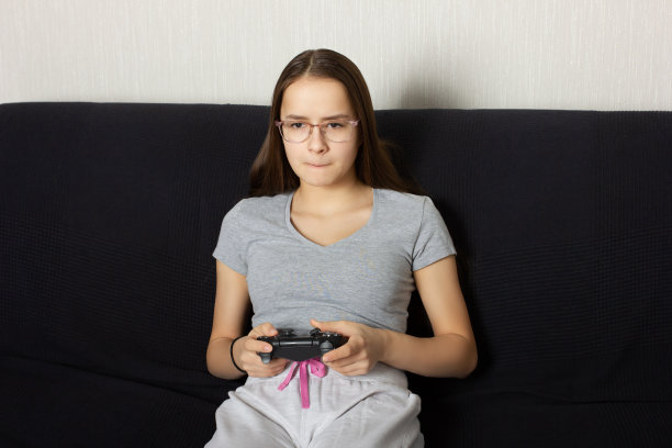 年轻的欧洲黑发少女在家里玩电子游戏。真正的情感,兴奋图片下载