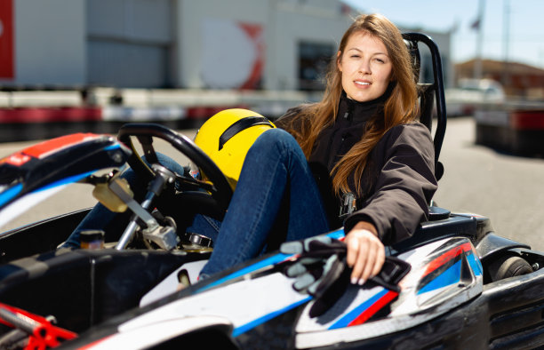 年轻女子戴着头盔坐在赛车在运动俱乐部图片下载