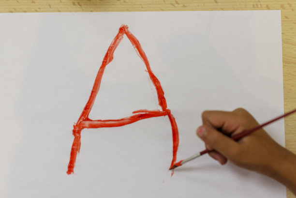 女孩在一张白色的纸上用画笔和彩色颜料作画:红，黄，棕色和蓝色。儿童的工艺品。回到学校。图片下载