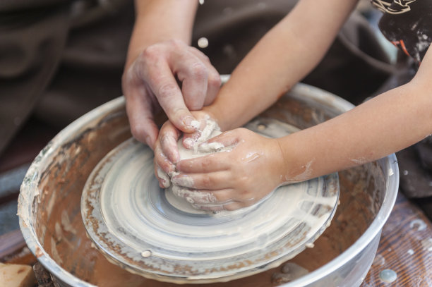 手工制作，手做粘土。师傅教学生在陶轮上做水罐。图片下载
