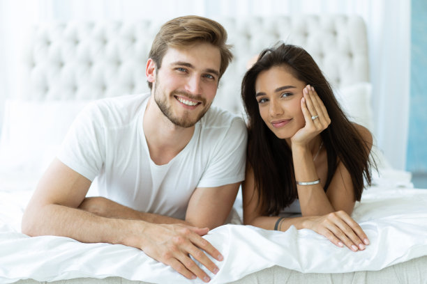 一对年轻幸福的夫妇躺在床上。图片下载