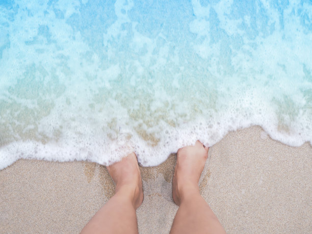 自拍女人的脚在夏天的海滩背景。图片下载