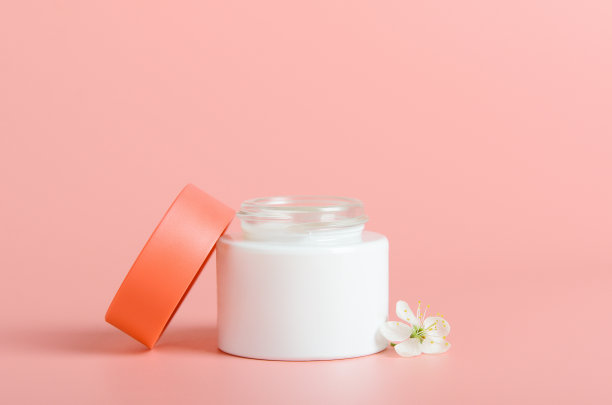 白瓶面霜，珊瑚色背景，红色盖子。化妆品、美容。最小的组合。图片下载