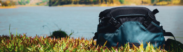 网络横幅春季活动概念来自旅行者或摄影师的相机包放在以湖景为背景的地板上图片下载