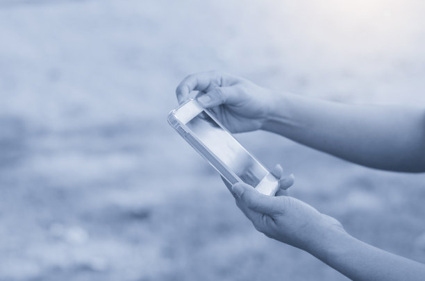 近距离的女人用手打字手机和触摸屏工作搜索与应用程序设备在公园与日出和模糊的自然背景复古风格。图片下载