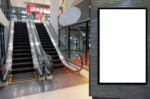 空白展示广告牌或广告灯箱为您的短信或媒体内容，在现代百货商场的自动扶梯前，商业和营销的概念图片下载