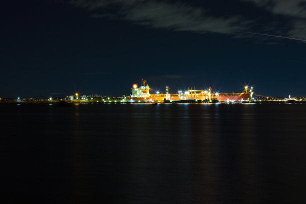 海湾在夜晚与油轮在炼油厂港口和城市天际线，背景与复制空间图片下载