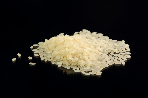 一撮白米长粒孤立在黑色镜面背景上。图片下载