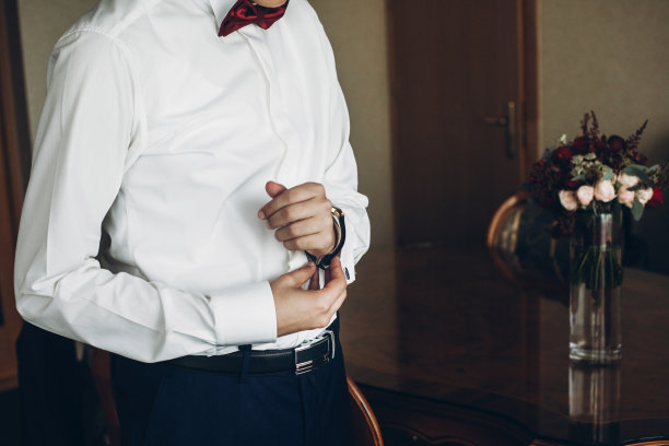 新郎在婚礼前的早上做好准备，在衬衫上戴上袖扣图片下载