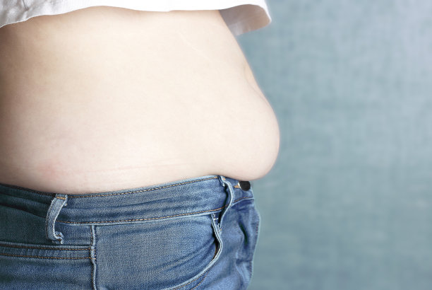 腹部赘肉在蓝色背景上，侧视图图片下载