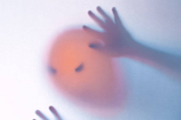 万圣节模糊背景。玻璃后面一个颜色像南瓜的鬼魂。可怕的噩梦图片下载