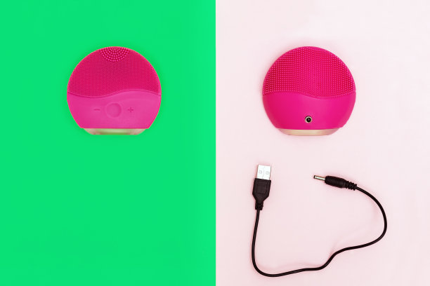 硅胶刷用于洗面和充电线在明亮的纸张背景上。红色电刷前后。美容小工具。面部护理。平的。前视图。图片下载