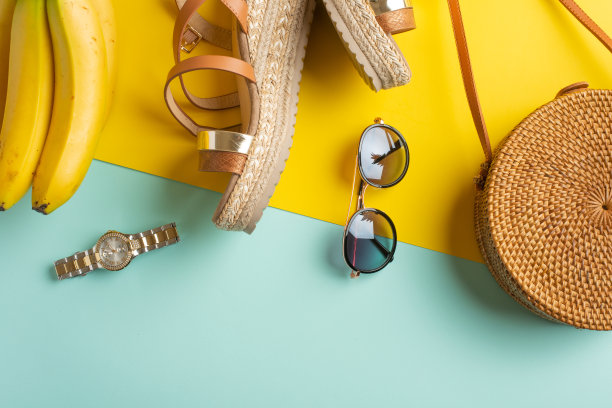 夏天五颜六色的柳条时尚包，热带菠萝和女鞋，太阳眼镜和手表。夏日时尚，假日概念。平的。黄色的蓝色背景。水平的照片图片下载