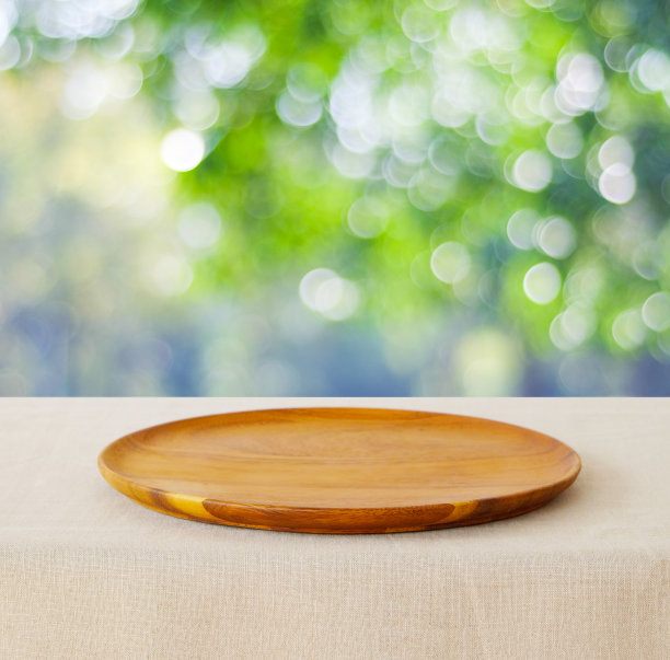 食物背景，空的木制盘子，托盘厨房产品展示在桌子上模糊的绿树自然花园与散景灯在夏季背景，木制盘子和公园户外食物横幅图片下载