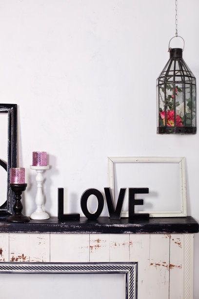 这个木字是爱。壁炉上放着两个烛台，上面放着蜡烛和一个木制的“爱”字。木刻情书。装饰房间的元素。情人节。哥特。阁楼图片下载