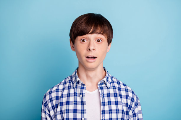 肖像惊讶的人看起来穿着格子衬衫孤立在蓝色背景图片下载