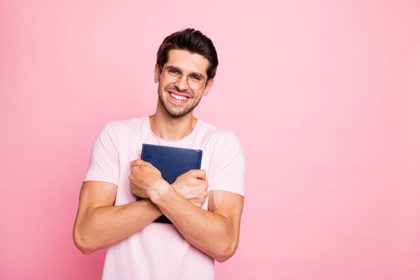 他的肖像，他很好，有吸引力，可爱，和平，快乐，快乐，聪明的家伙双手抱在一起，拥抱图书图书馆孤立在粉红色柔和的背景图片下载