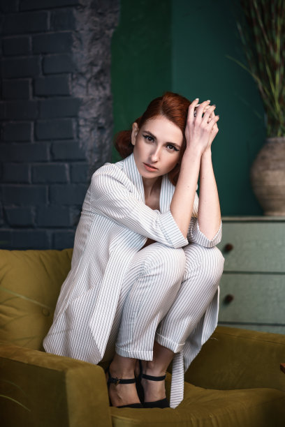 漂亮的红发瘦弱的年轻女子穿着白色的宽松套装图片下载